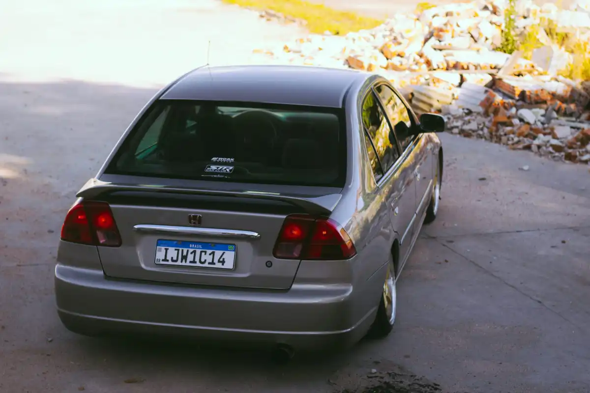 a silver car parked in a driveway next to a tree