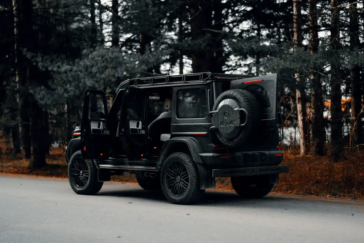 A black jeep driving down a road next to a forest
