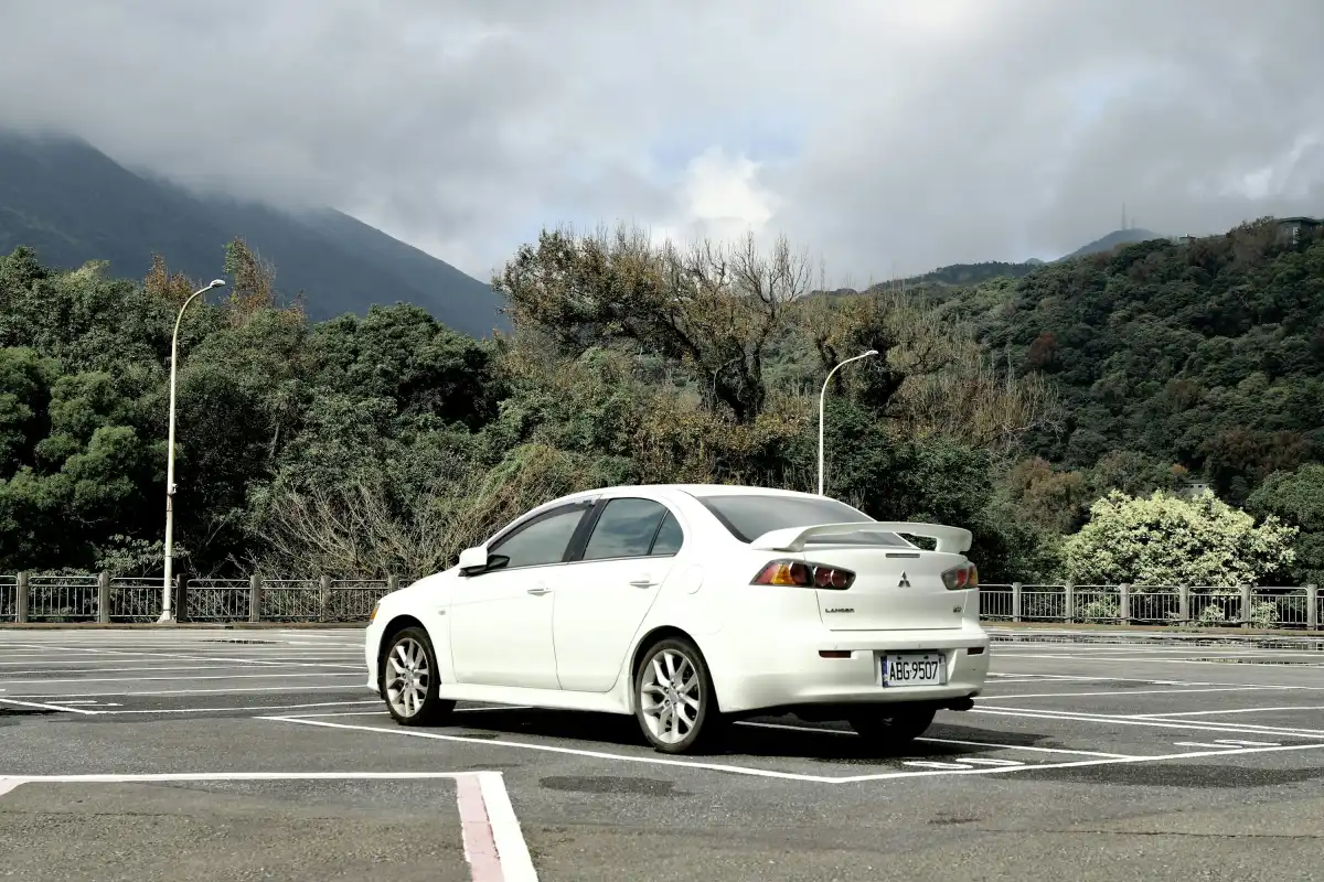 white sedan on road near green trees during daytime