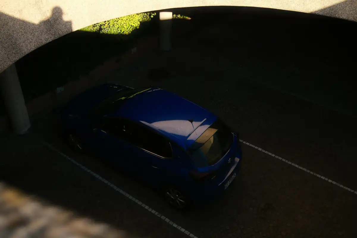 A blue car is driving under a bridge