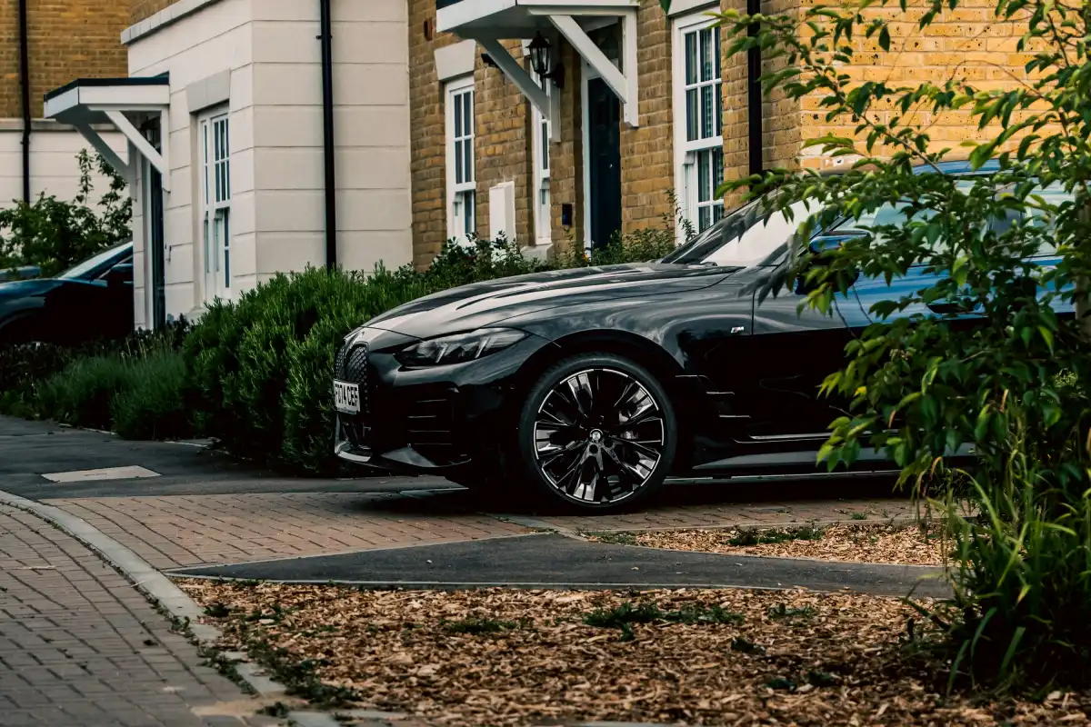 A black car is parked in front of a house.